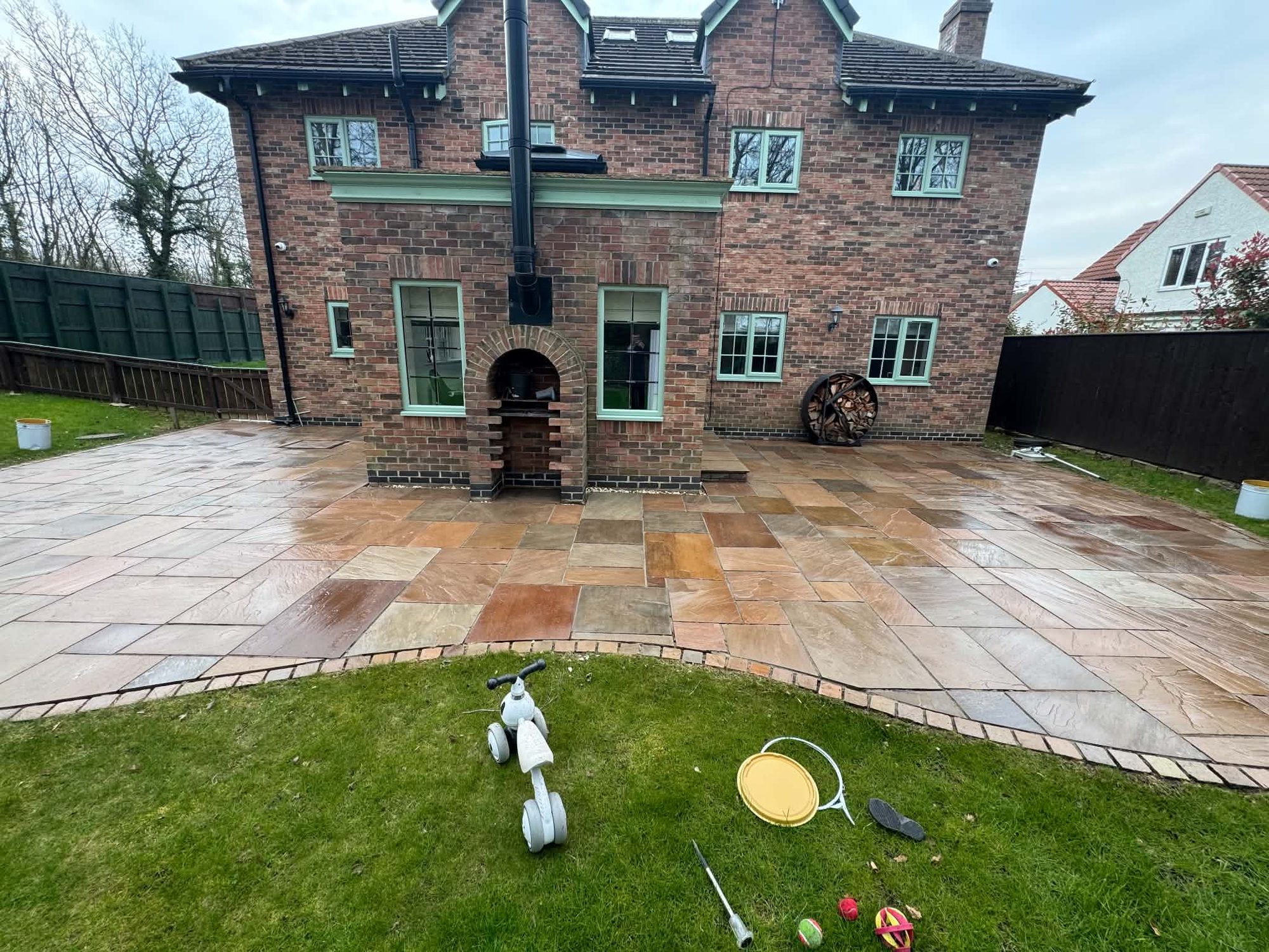 A freshly cleaned Indian sandstone patio behind a large family home